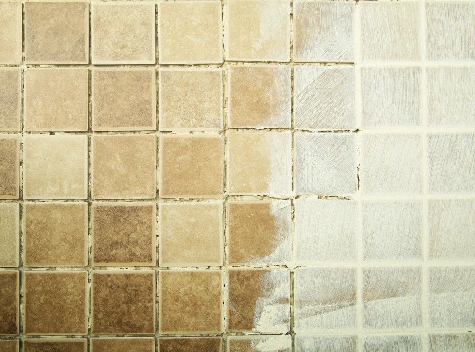 Tiles half cleaned, showing dirty brown tiles next to clean light tan tiles, highlighting the cleaning process.