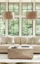A bright living room with tall windows covered by striped roller shades and patterned floor-length curtains.