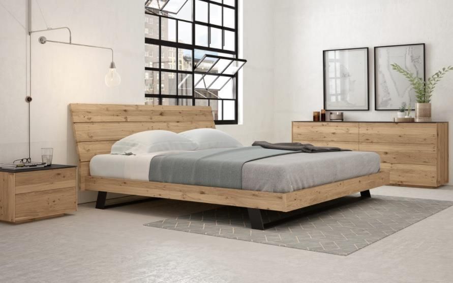 A modern bedroom features a cream upholstered bed centered between two wooden nightstands with lamps against a green wall.