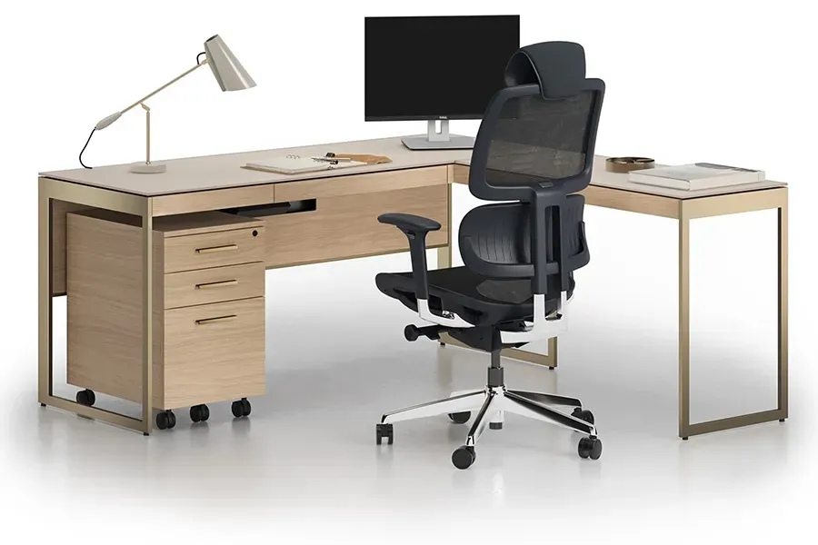 A modern, minimalist home office featuring a V-shaped glass desk, black office chair, and two open, angular bookshelves.