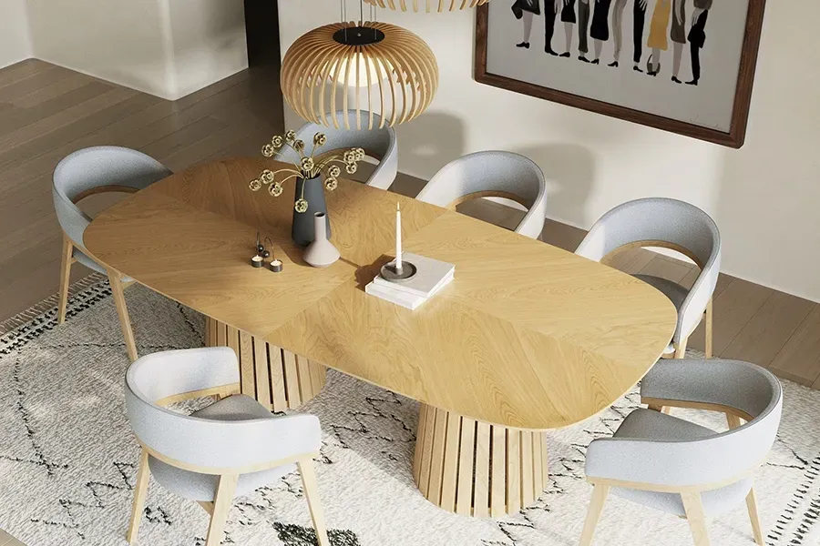 A glass-topped dining table with wooden legs, surrounded by white chairs in a room with floor-to-ceiling blinds and art.