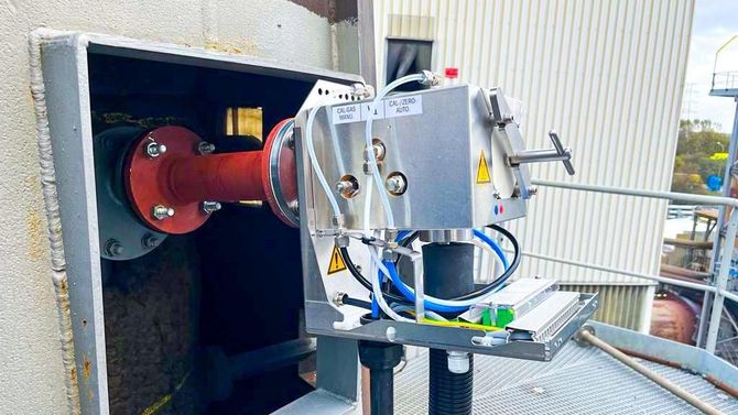 A machine is sitting on top of a metal platform next to a pipe.