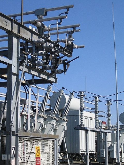 Factory generating electricity, symbolized by a lightning bolt, with a person holding a lightbulb.
