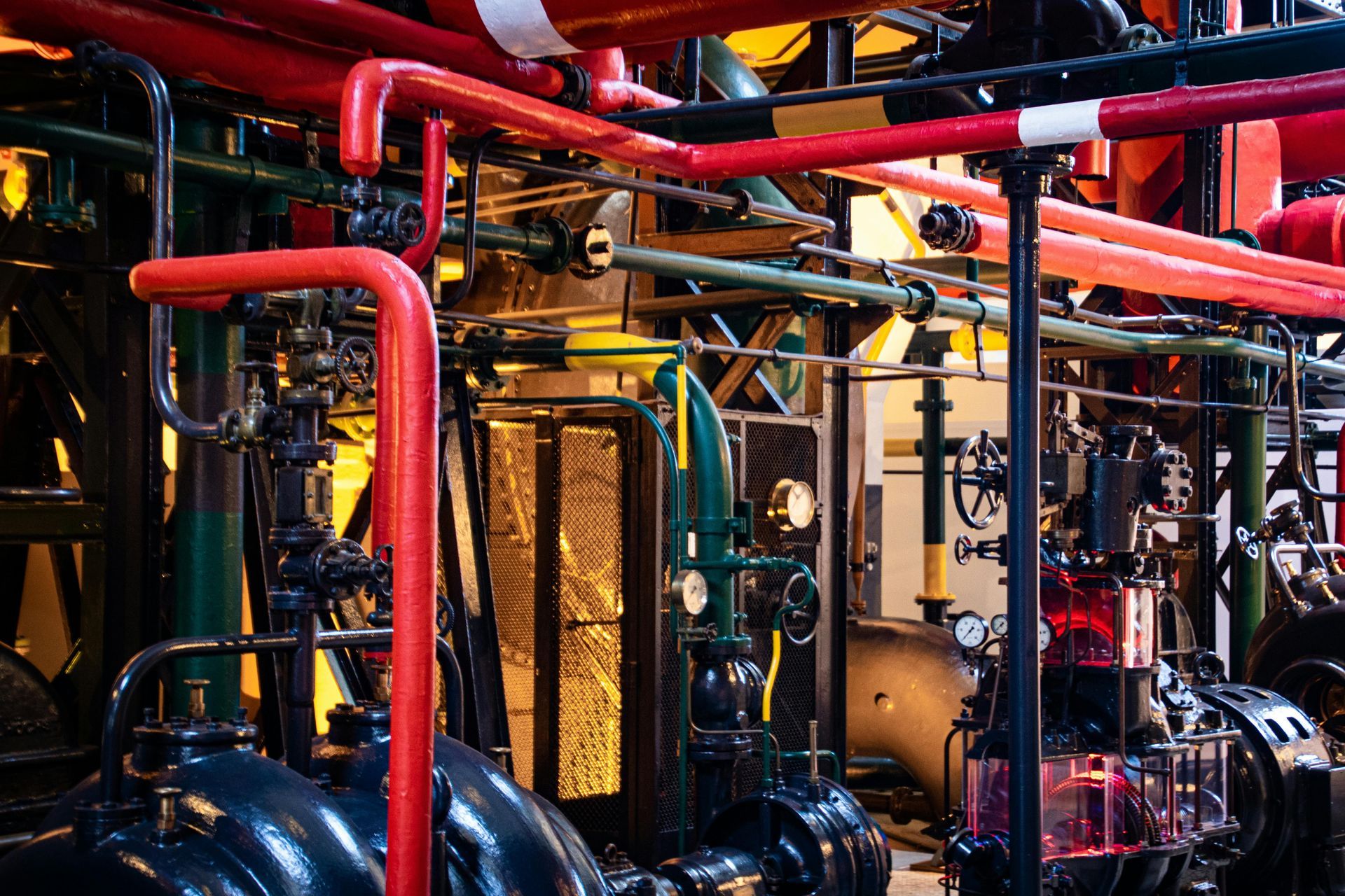 Red and green pipes and machinery in an industrial setting, possibly a factory or power plant.
