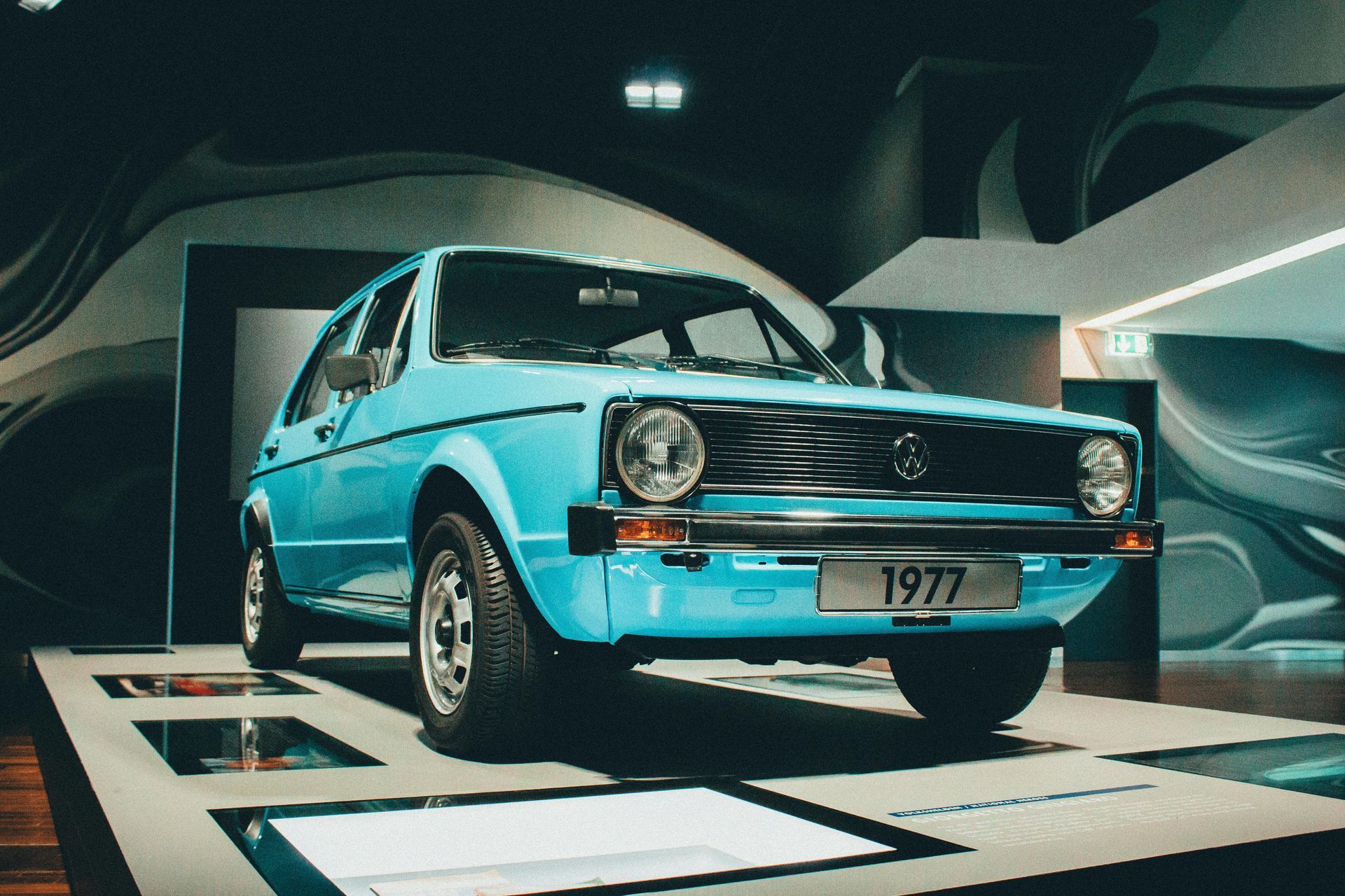 Light blue 1977 Volkswagen Golf on display inside a museum.