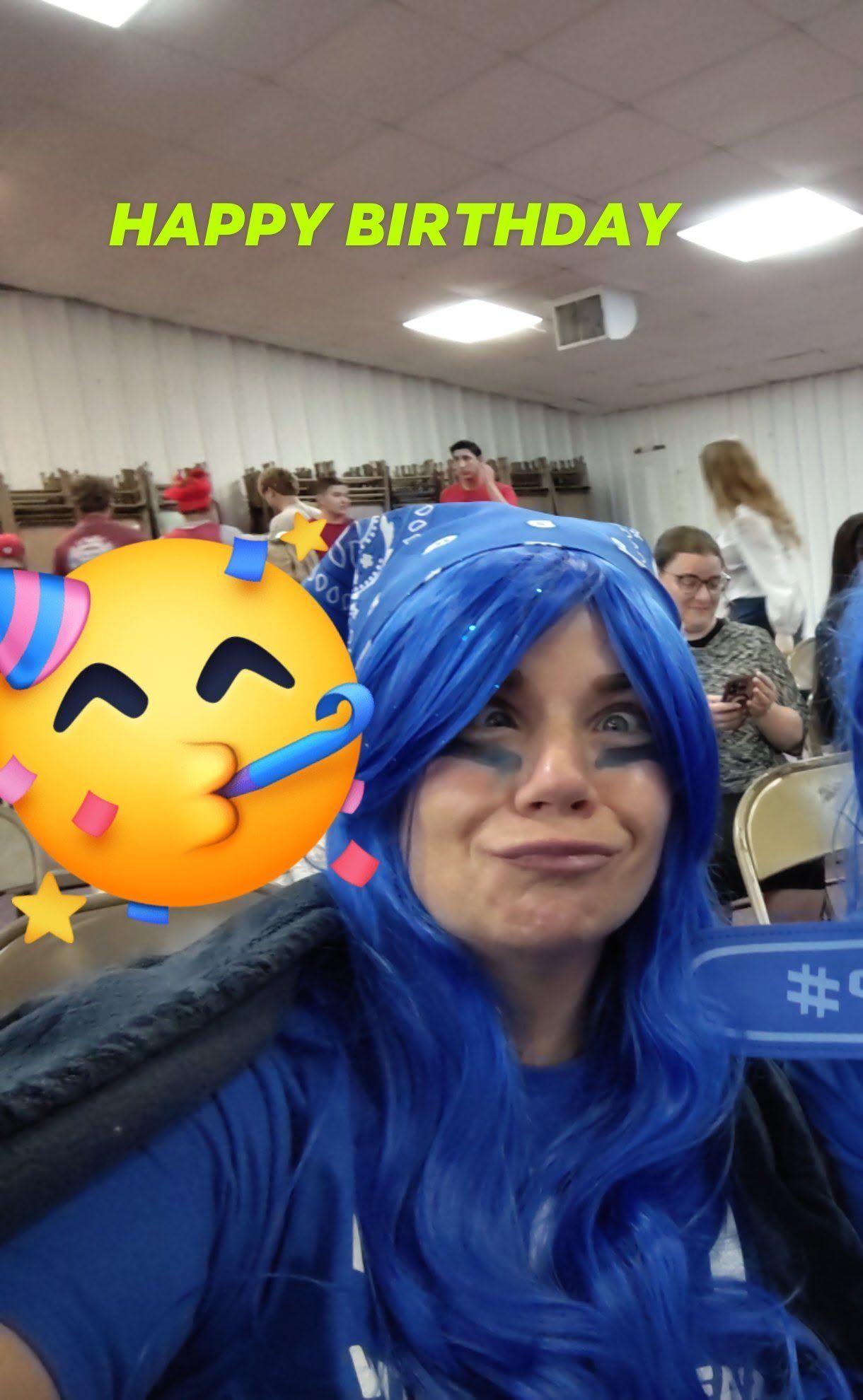 Birthday party selfie with a blue wig, smiling face sticker, and “HAPPY BIRTHDAY” text at the top