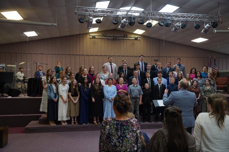 Choir and congregation on a church stage, with a man speaking to the group from the audience.