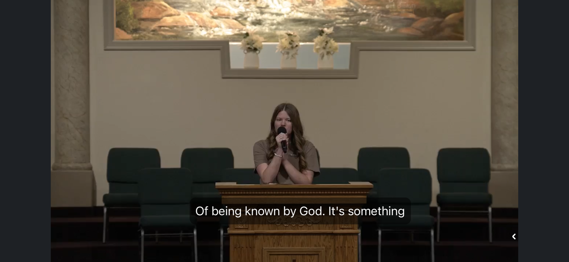 single lady talking in front of a bunch of green chairs on a microhone