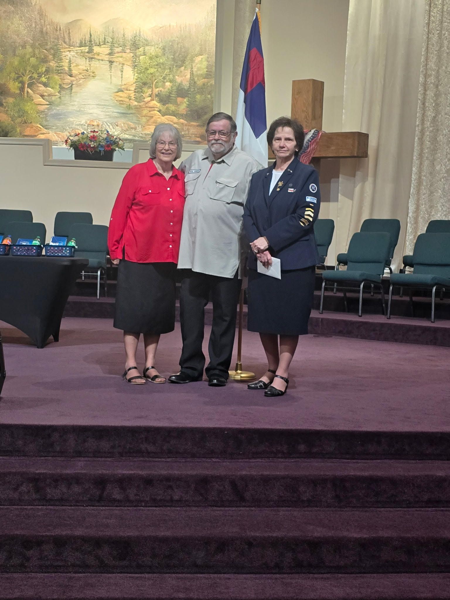 lady man with arm around each other standing on stage with a lady in a uniform