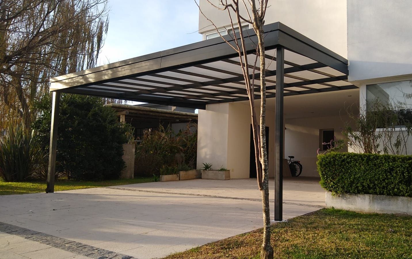 Una cochera con un toldo encima está en frente de una casa.