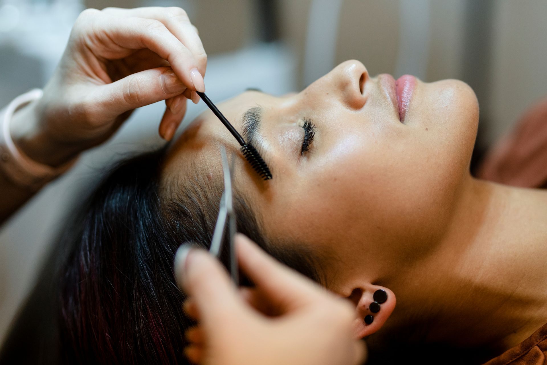 Person having eyebrow tweezed with a tweezer in a close-up beauty treatment scene