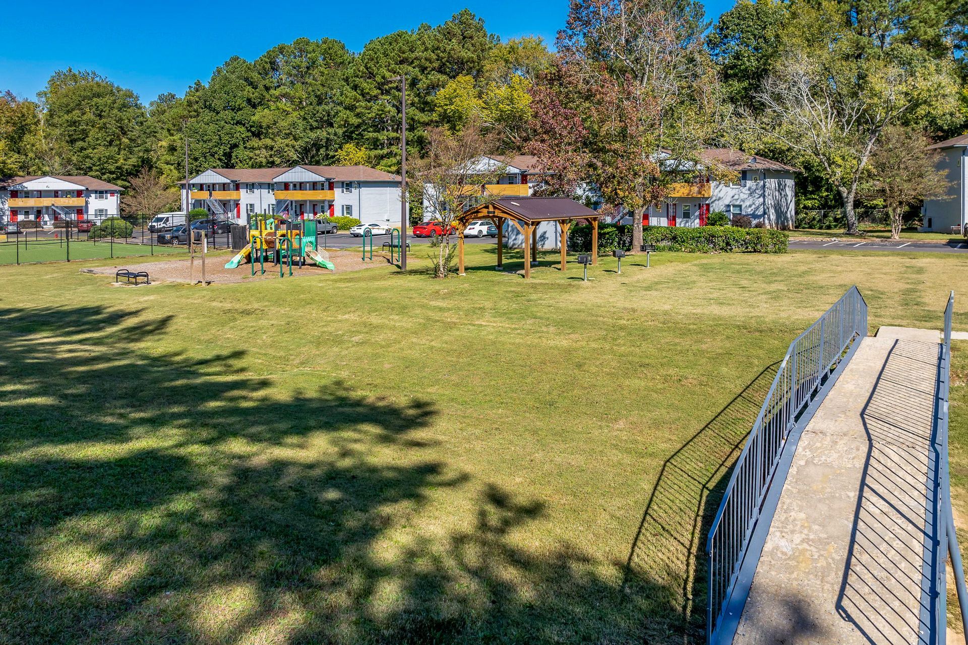 Grassy area with apartments in the background under a blue sky.