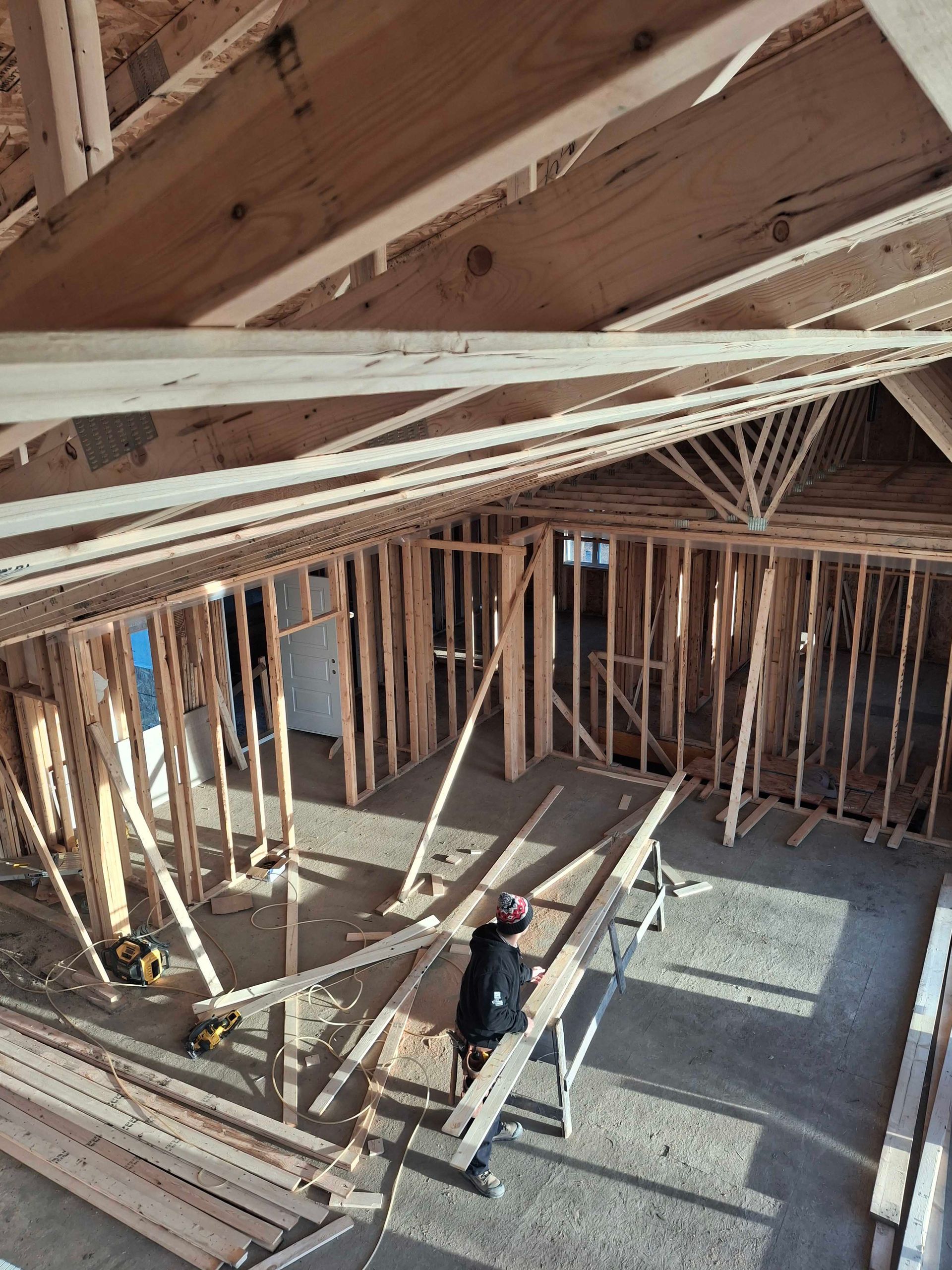 Interior view of a building under construction, showing wooden framing and roof rafters.