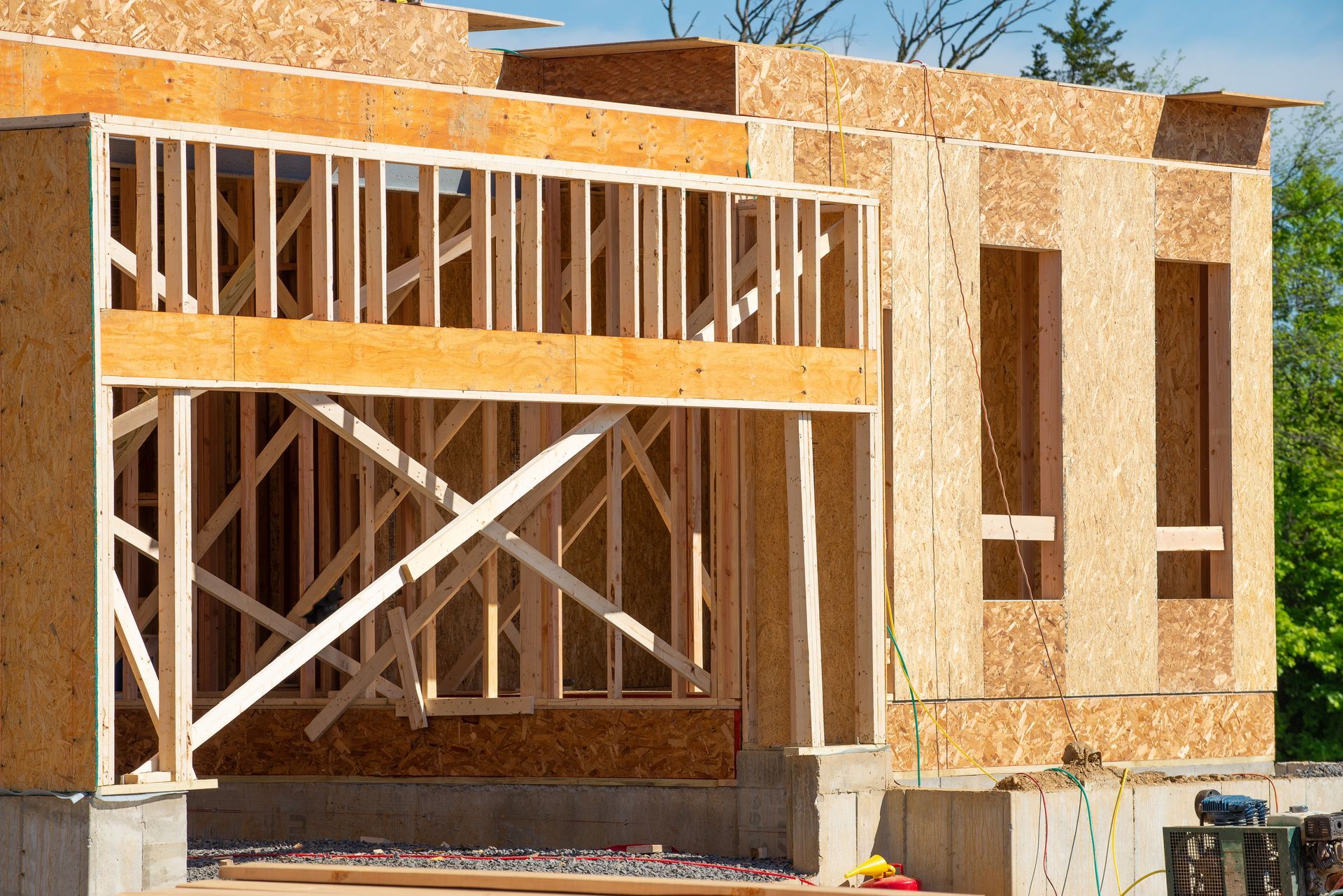 Wooden house under construction; exposed framing and OSB siding.