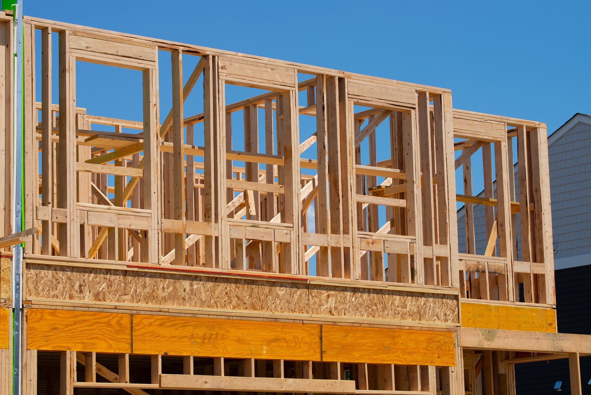 Wood frame construction of a building with window openings against a blue sky.