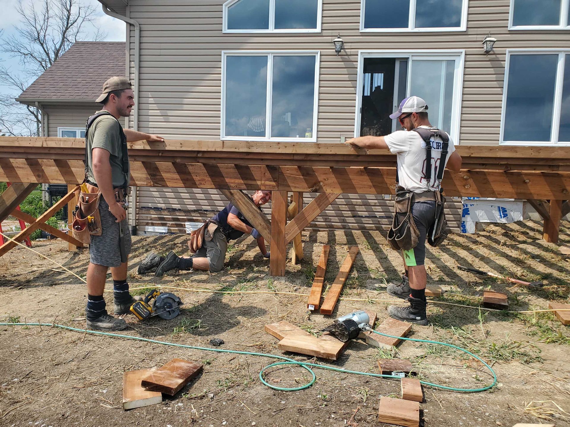 Construction workers building a wooden deck outdoors.