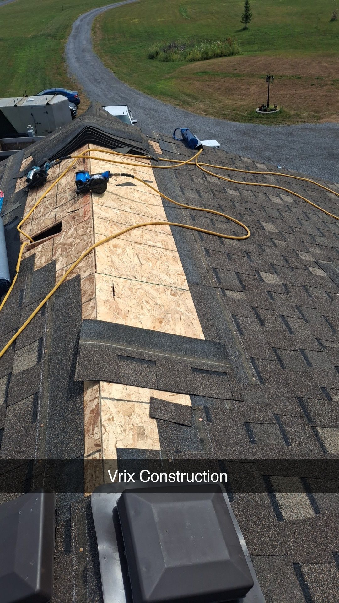Roofing work in progress; new plywood on ridge, tools, and asphalt shingles visible on a sunny day.