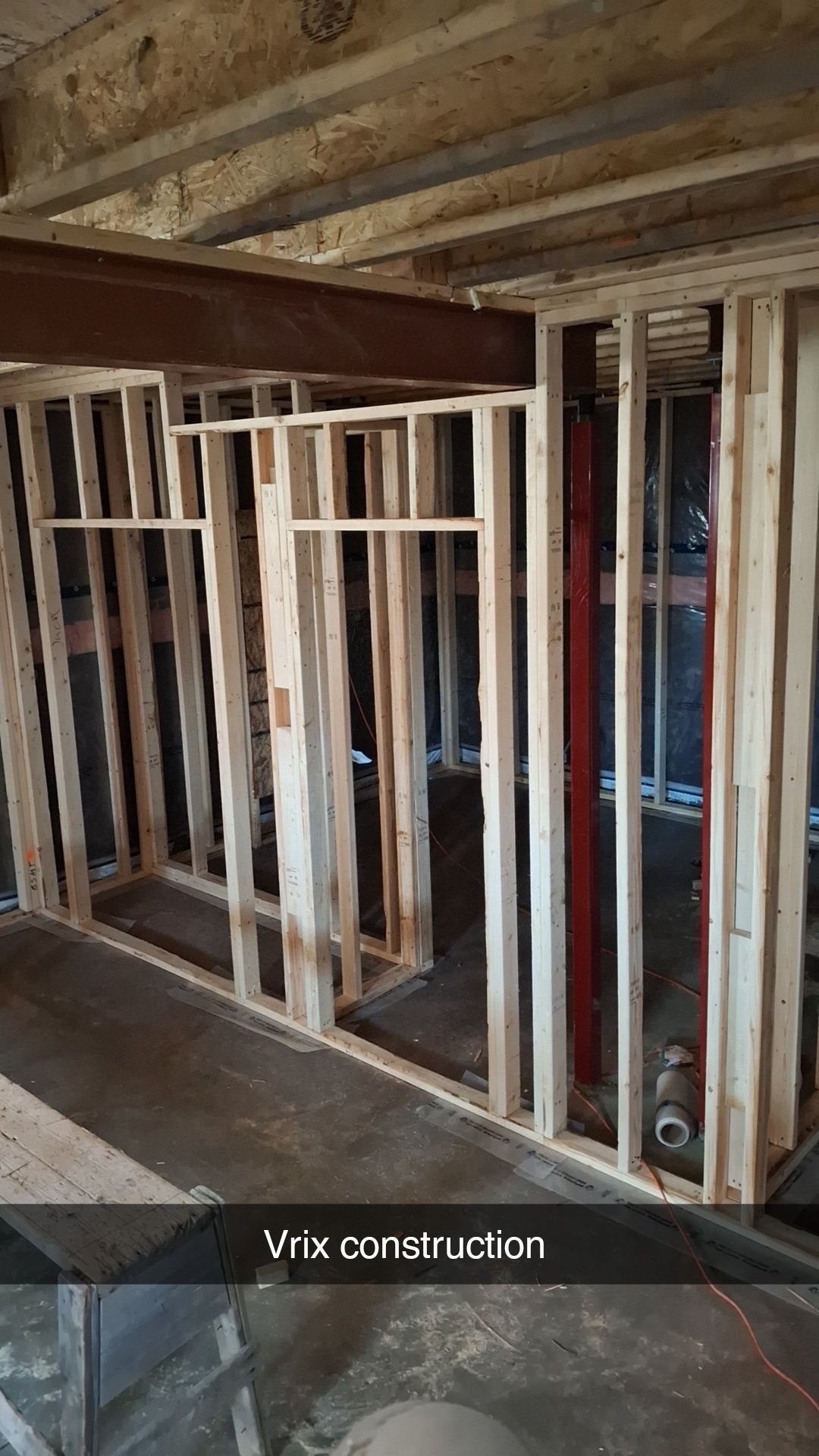 Framing for interior walls, wooden studs, concrete floor, exposed ceiling beams.