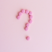 Pink question mark made of small beads on a pale pink background