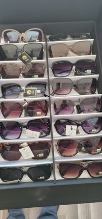 Stacked display of sunglasses in clear cases, with assorted dark and pink-tinted lenses on shelves