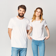 Two people in white T-shirts and blue jeans standing side by side against a plain background