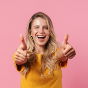 Smiling person in a yellow shirt giving two thumbs up against a pink background