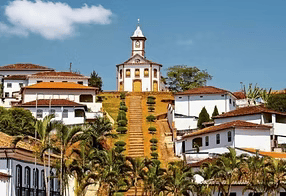 Vila branca na encosta de uma colina com telhados de telha vermelha e uma igreja