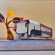 Ilustração moderna de um ônibus ao lado de uma árvore estilizada com folhas de outono sobre um fundo bege.
