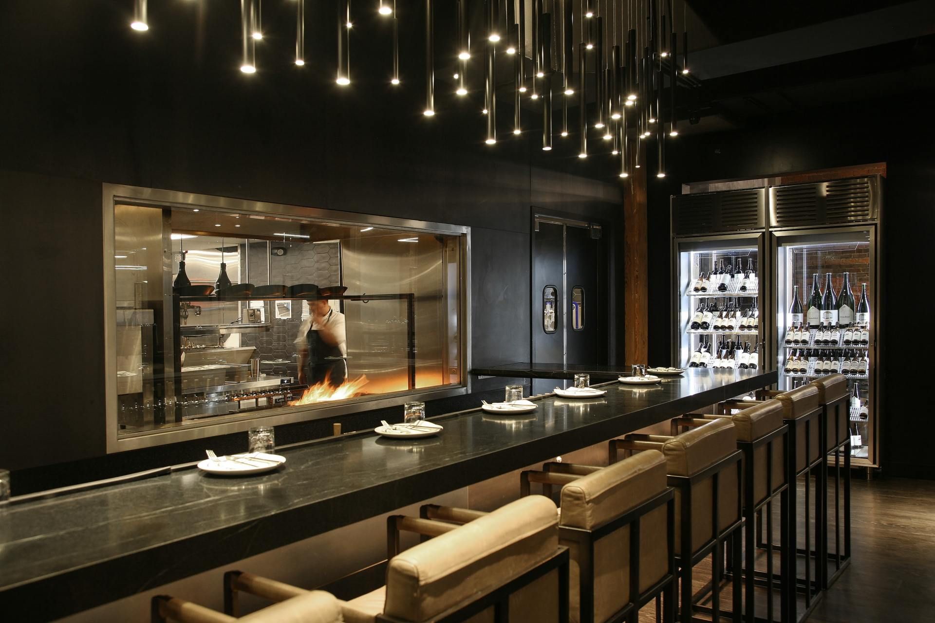 a long bar in a restaurant with a chef in the background
