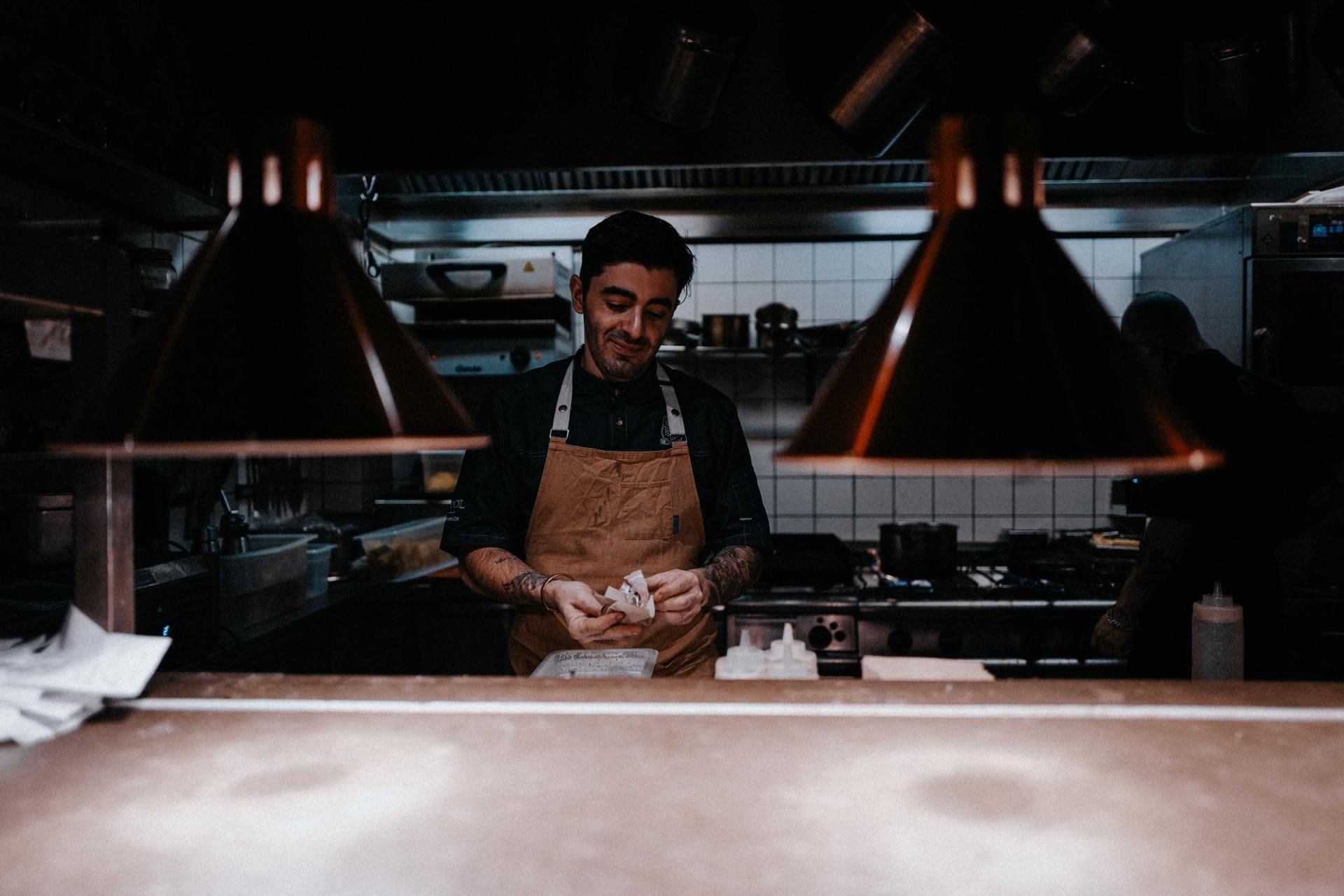 A man in an apron is preparing food in a kitchen