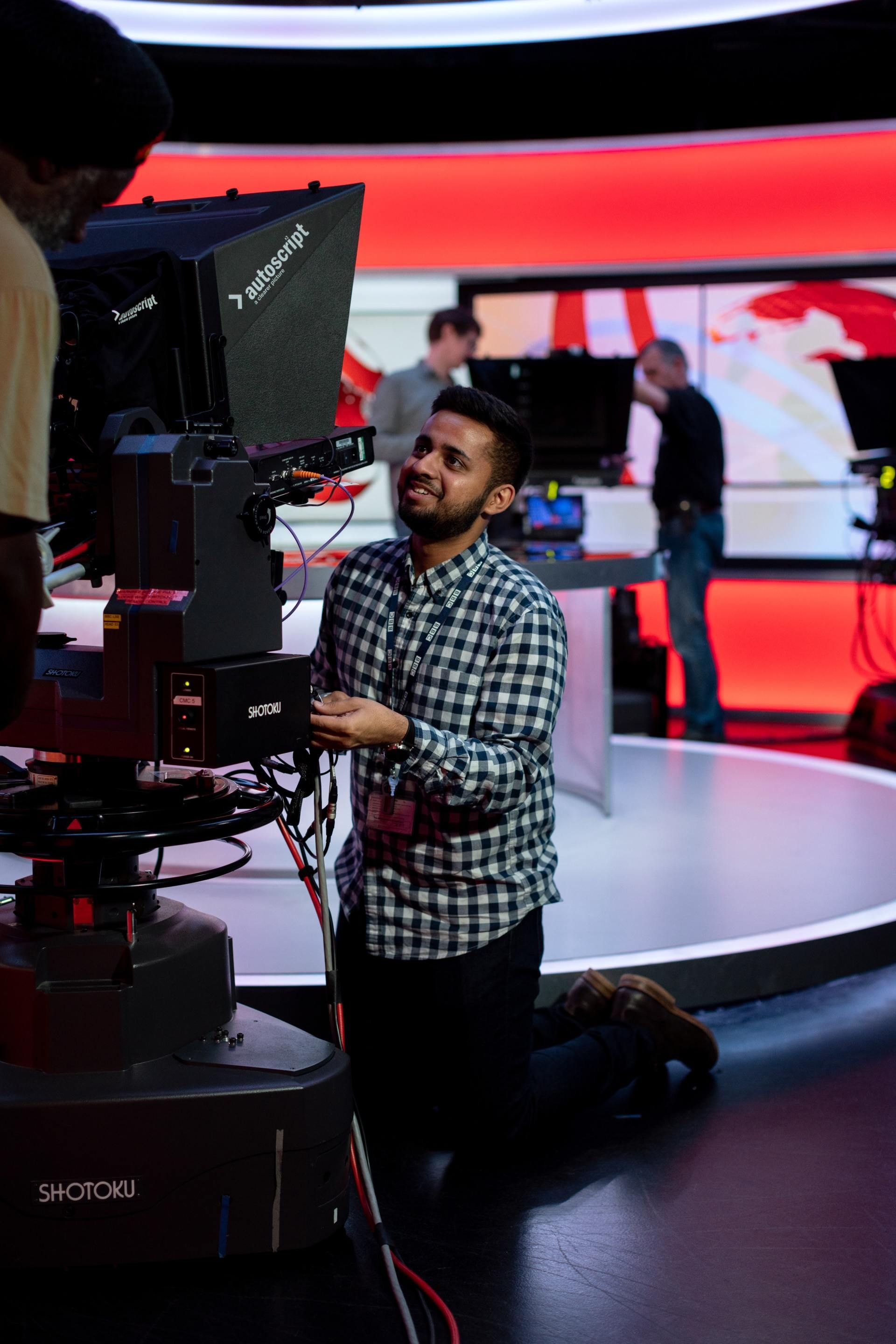 a man in a plaid shirt is kneeling in front of a camera that says capture on it