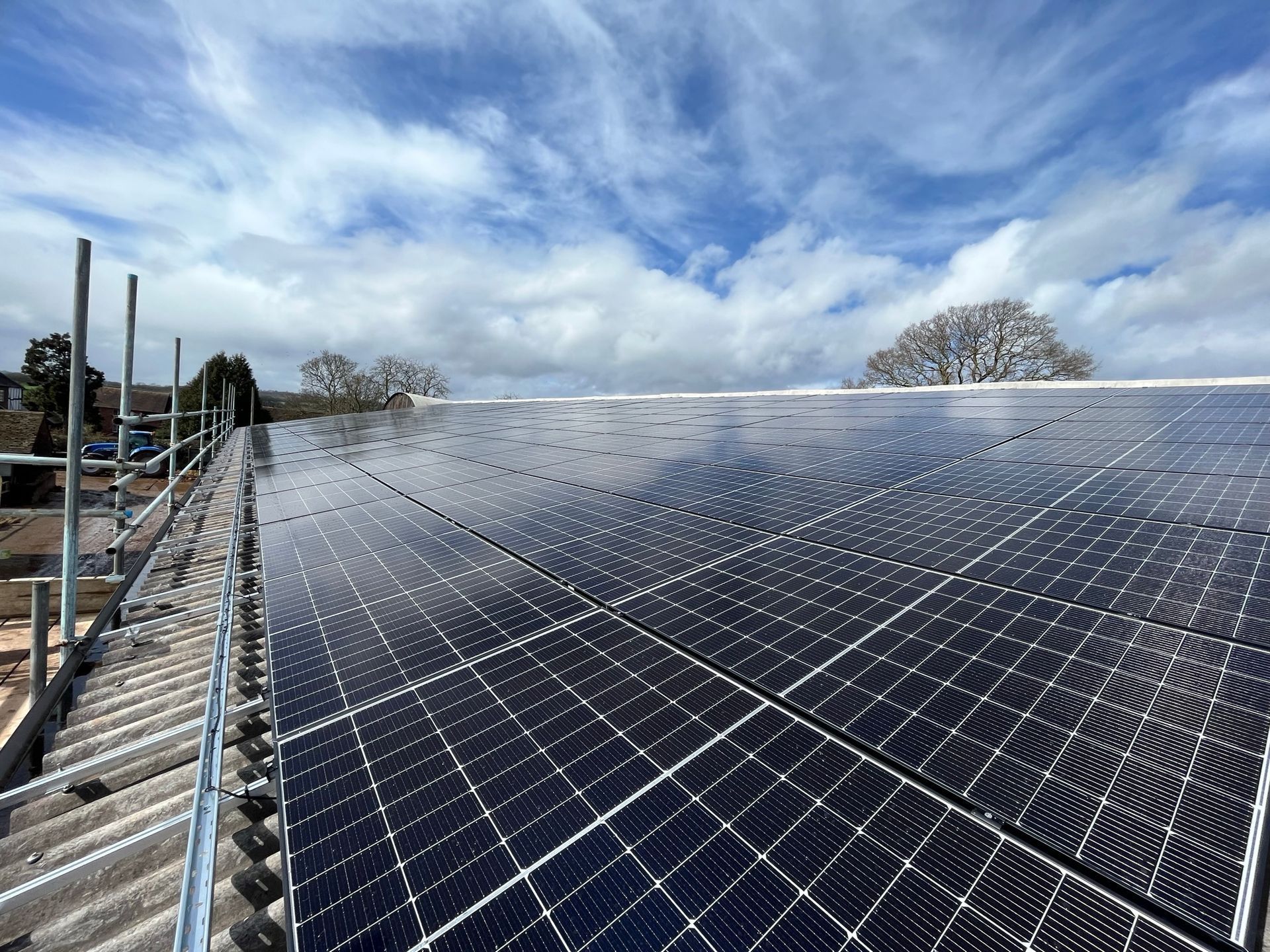 A row of solar panels on a roof with a blue sky in the background