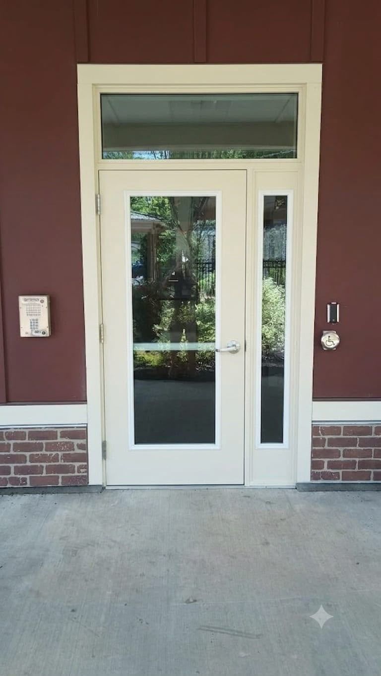 White-framed glass door entrance with sidelights on a maroon building exterior