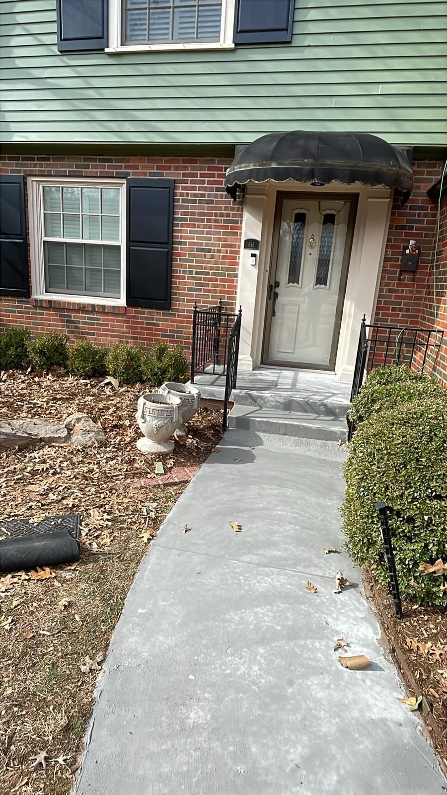 Brick building with a concrete walkway leading to a front door with an awning.