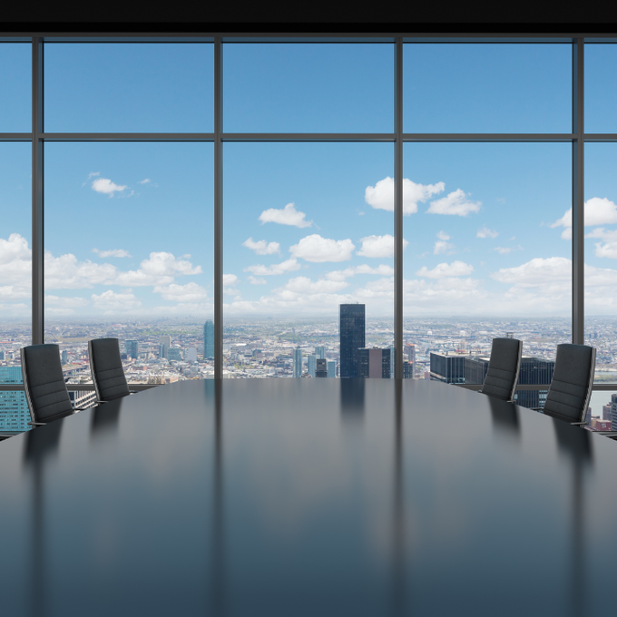 A conference room with a large table and chairs and a view of the city.
