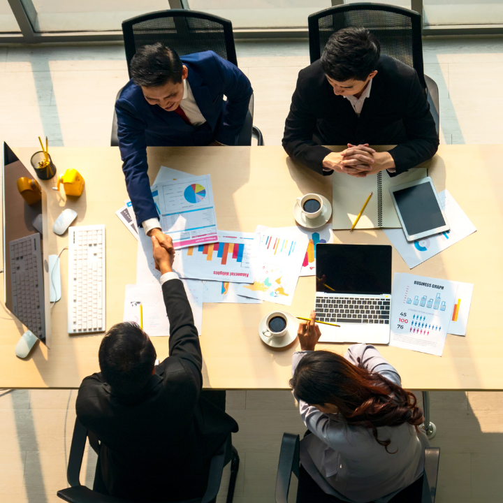 A group of people are sitting around a table shaking hands