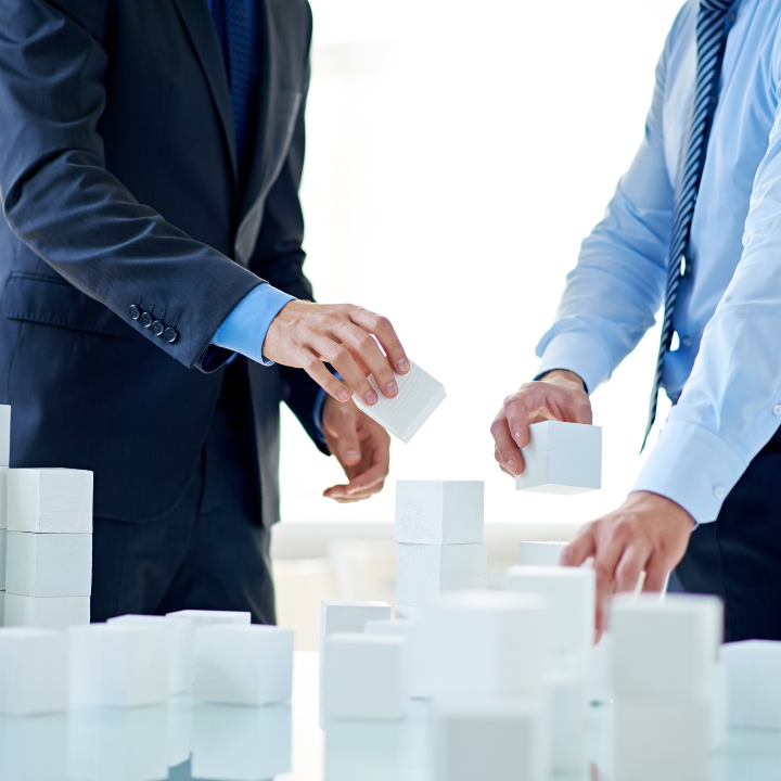 Two men are playing with white blocks on a table