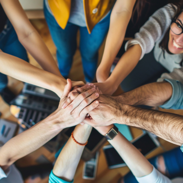 A group of people are putting their hands together in a circle.