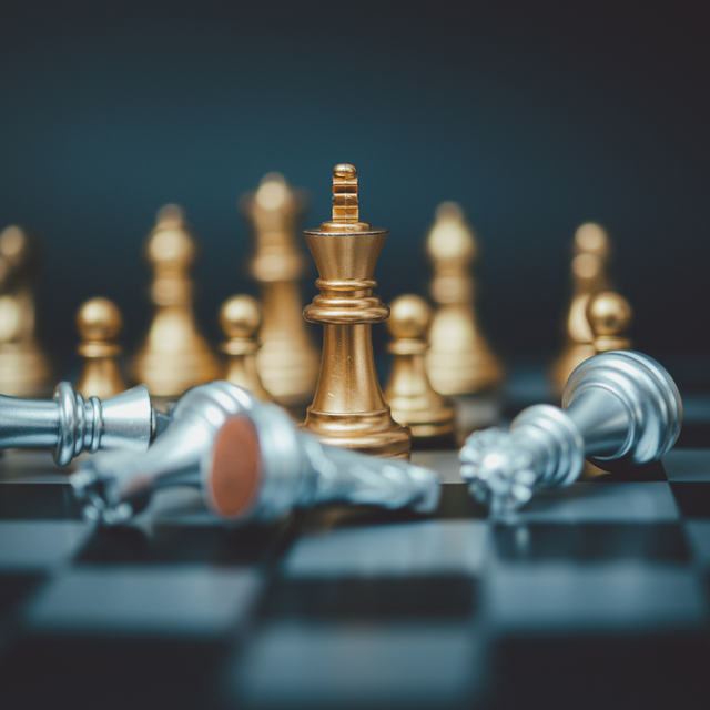 A group of gold and silver chess pieces on a chess board.