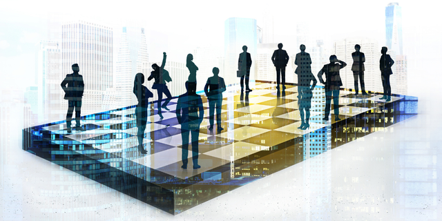 A group of people are standing on top of a chess board.