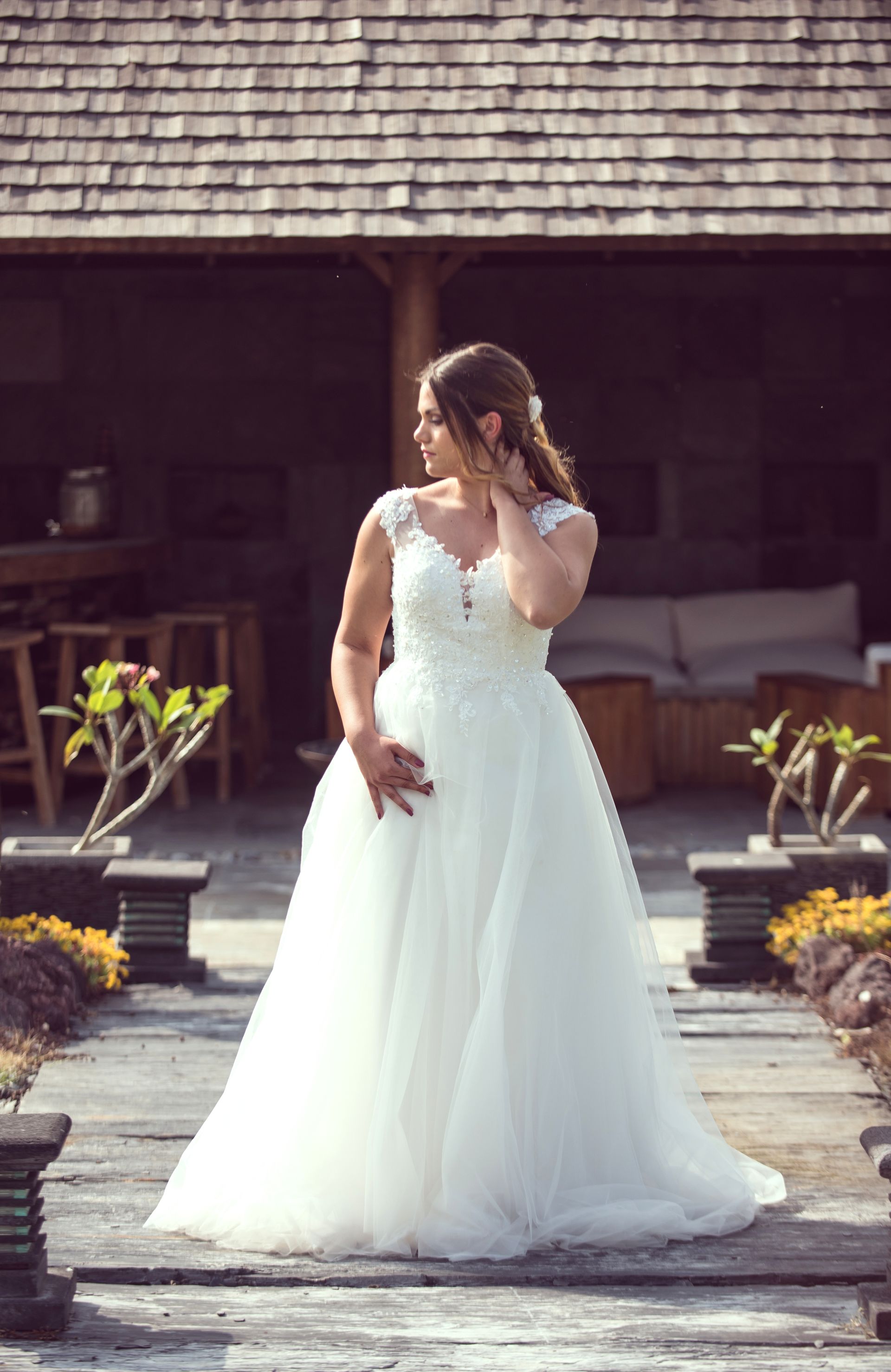 Une femme en robe de mariée blanche se tient devant un bâtiment.