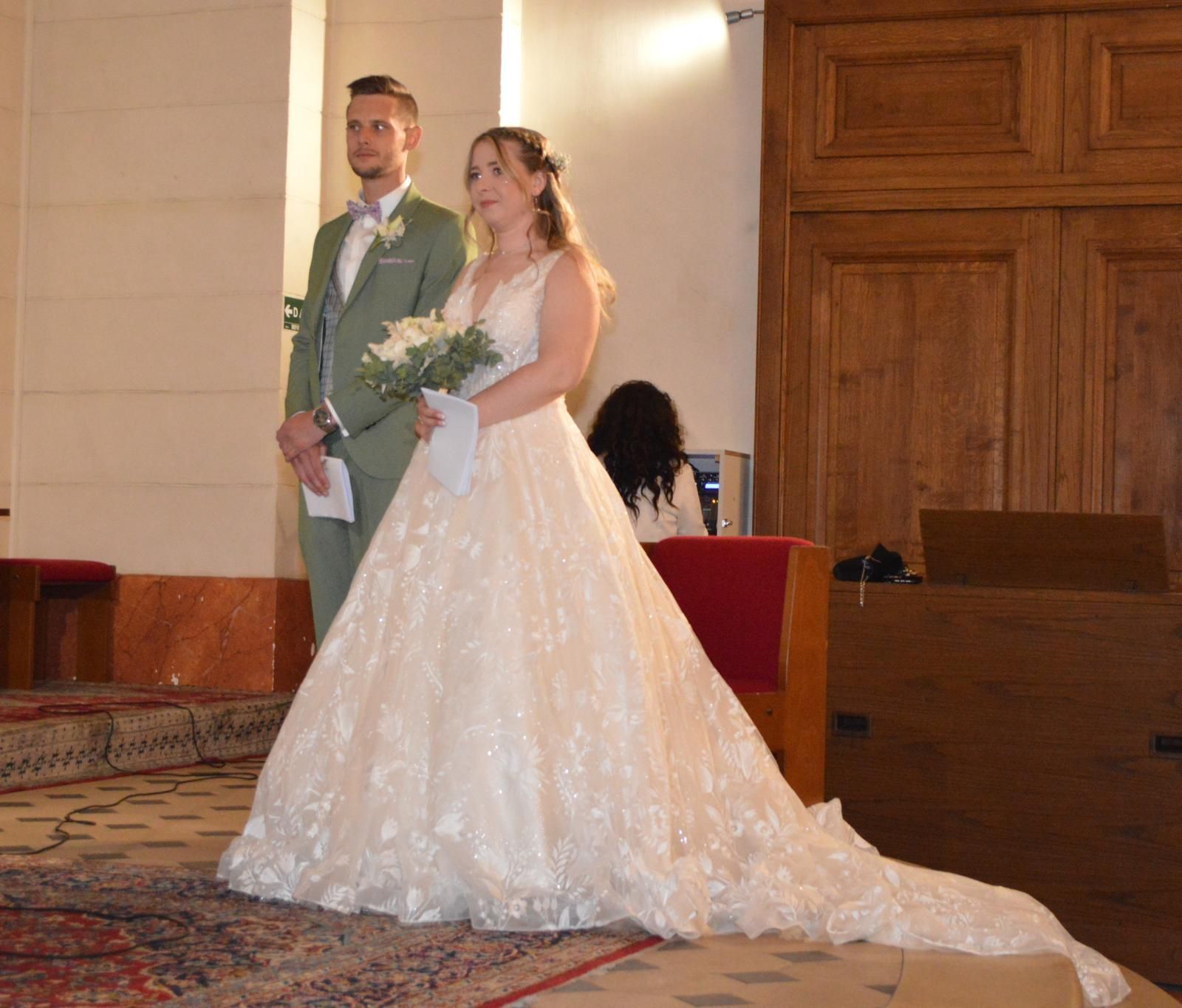 Une mariée et un marié se tiennent l'un à côté de l'autre dans une église.
