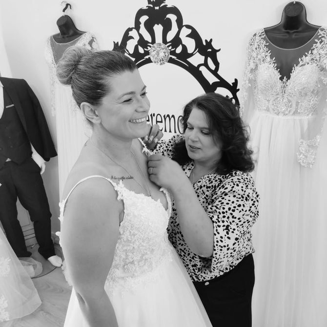 Une femme aide une autre femme avec sa robe de mariée