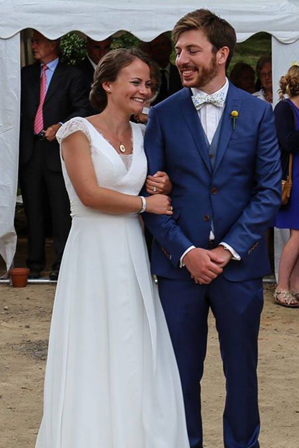 Une mariée et un marié posent pour une photo devant une tente blanche.