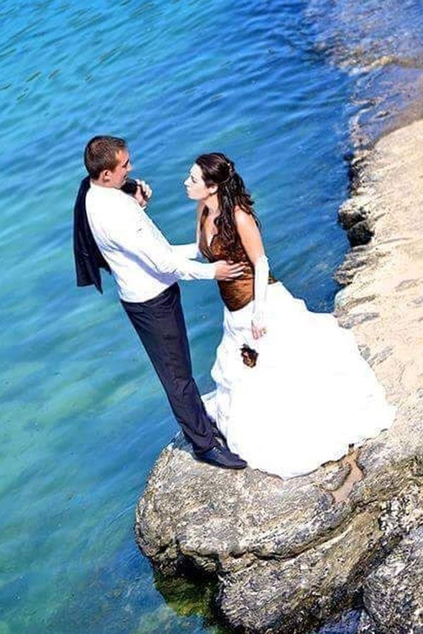 Une mariée et un marié se tiennent sur un rocher près de l'océan