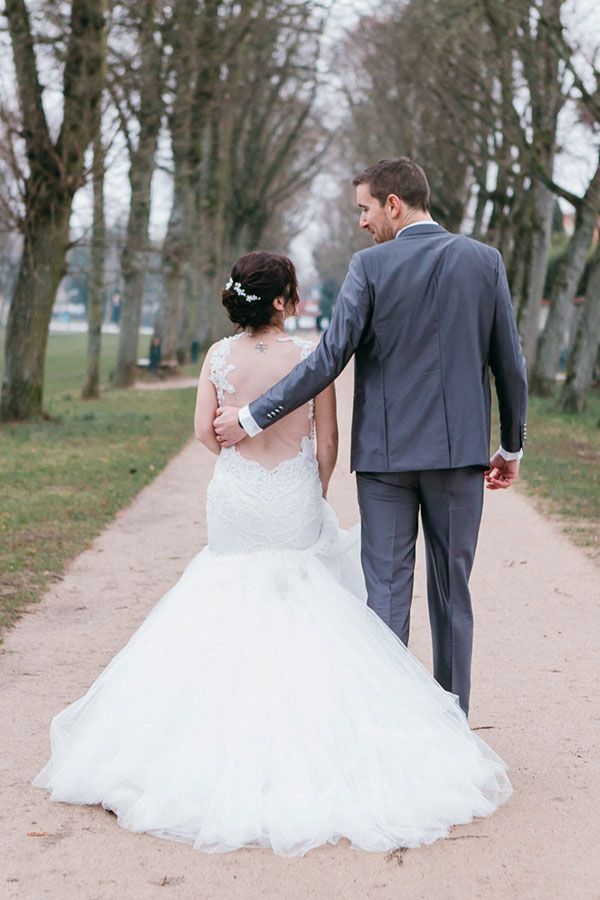 Une mariée et un marié marchent sur un chemin dans un parc.