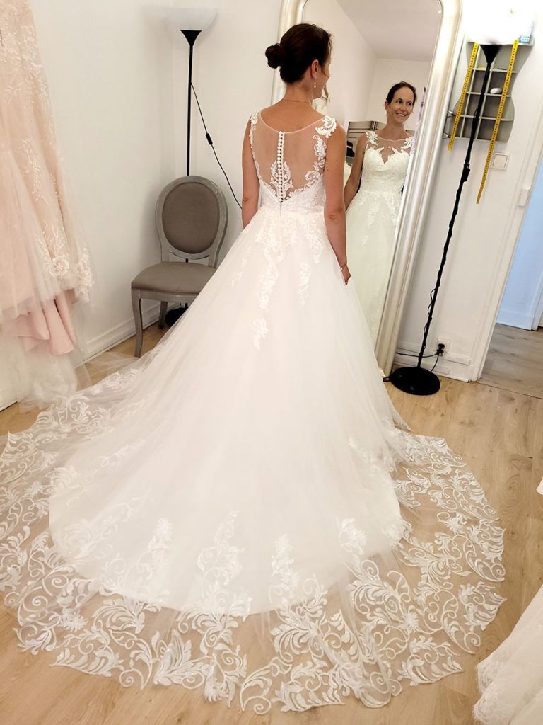 Une femme en robe de mariée se tient devant un miroir.