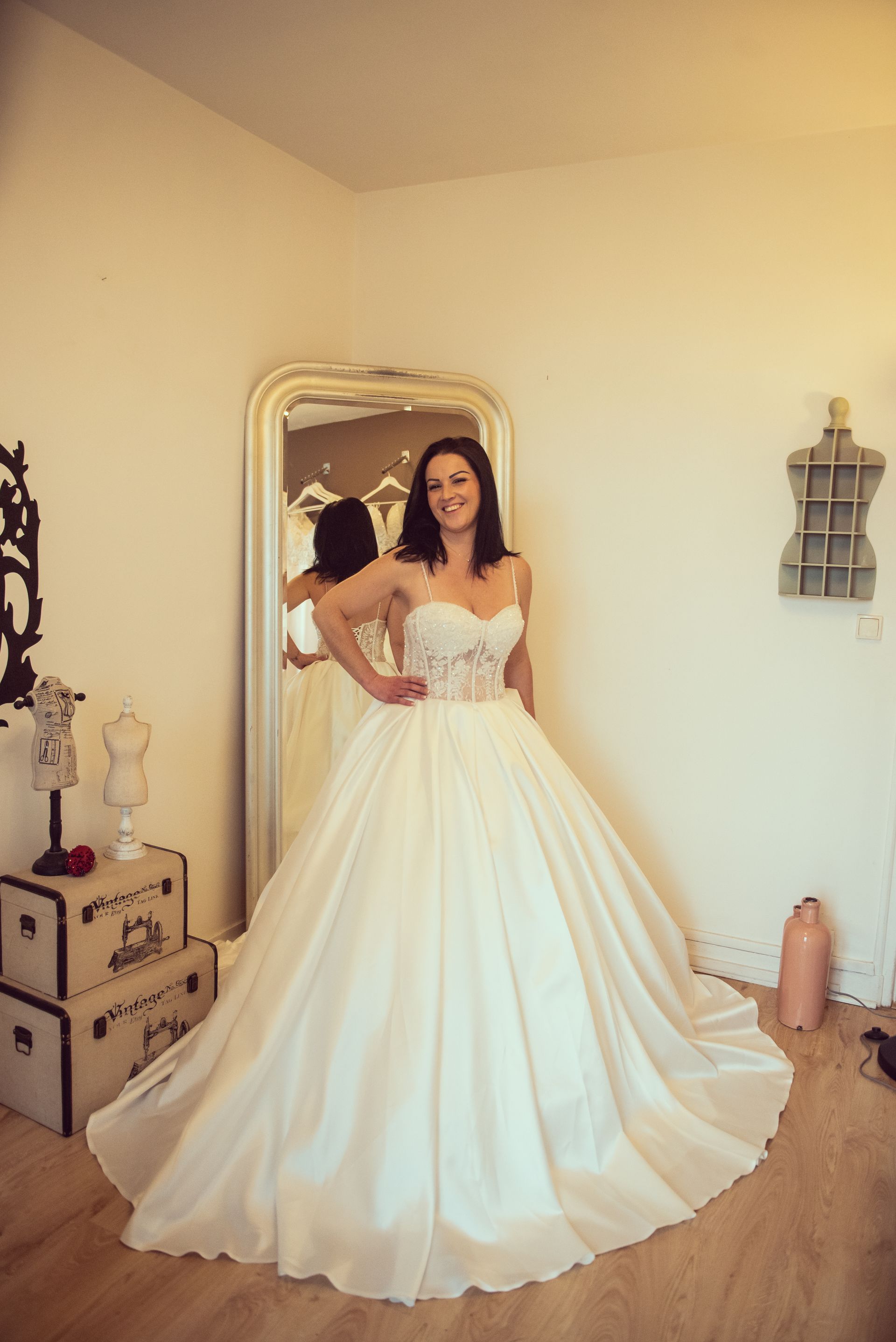 Une femme en robe de mariée se tient devant un miroir.