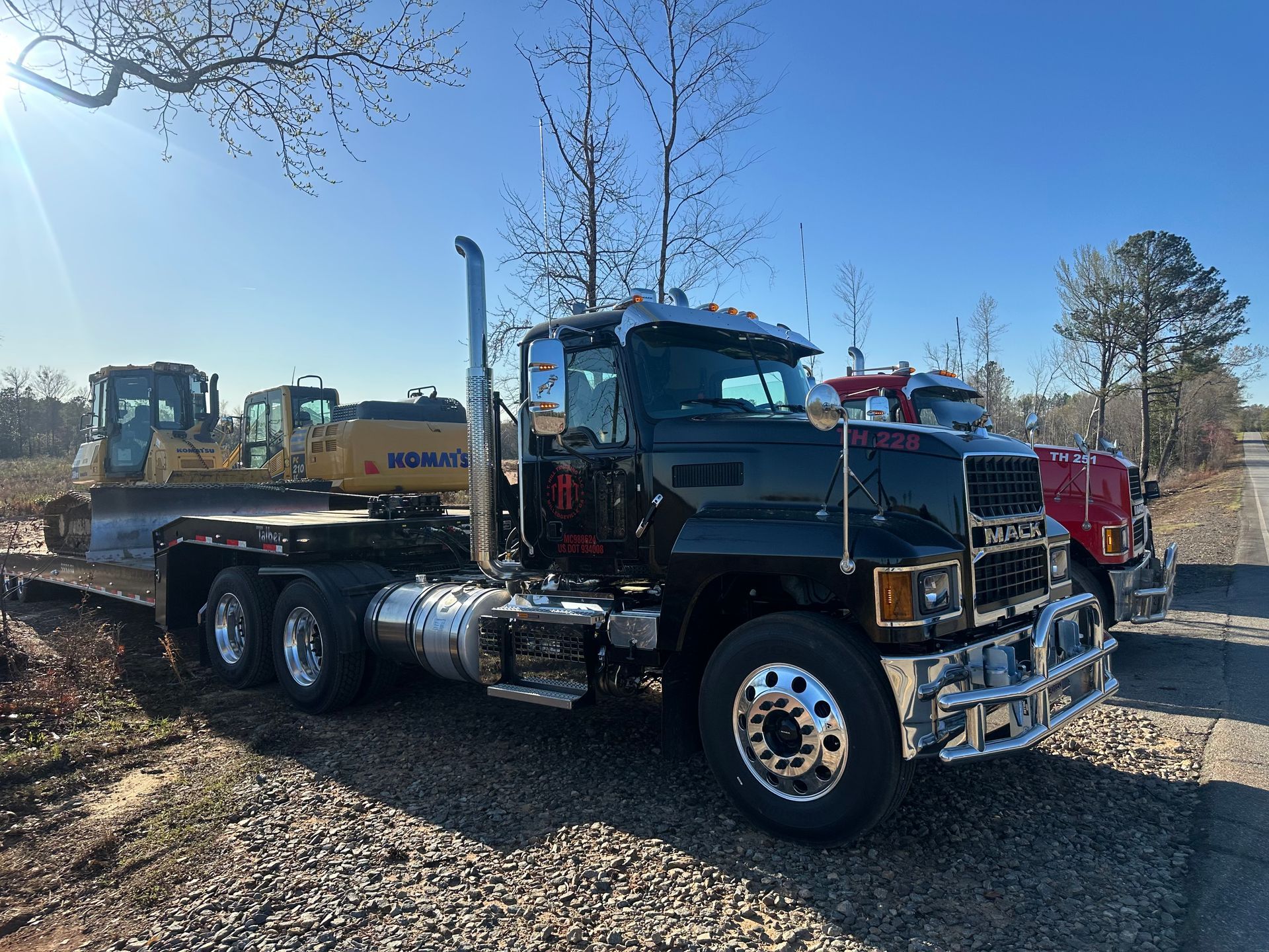 A truck is being towed by a crane in a dirt field.