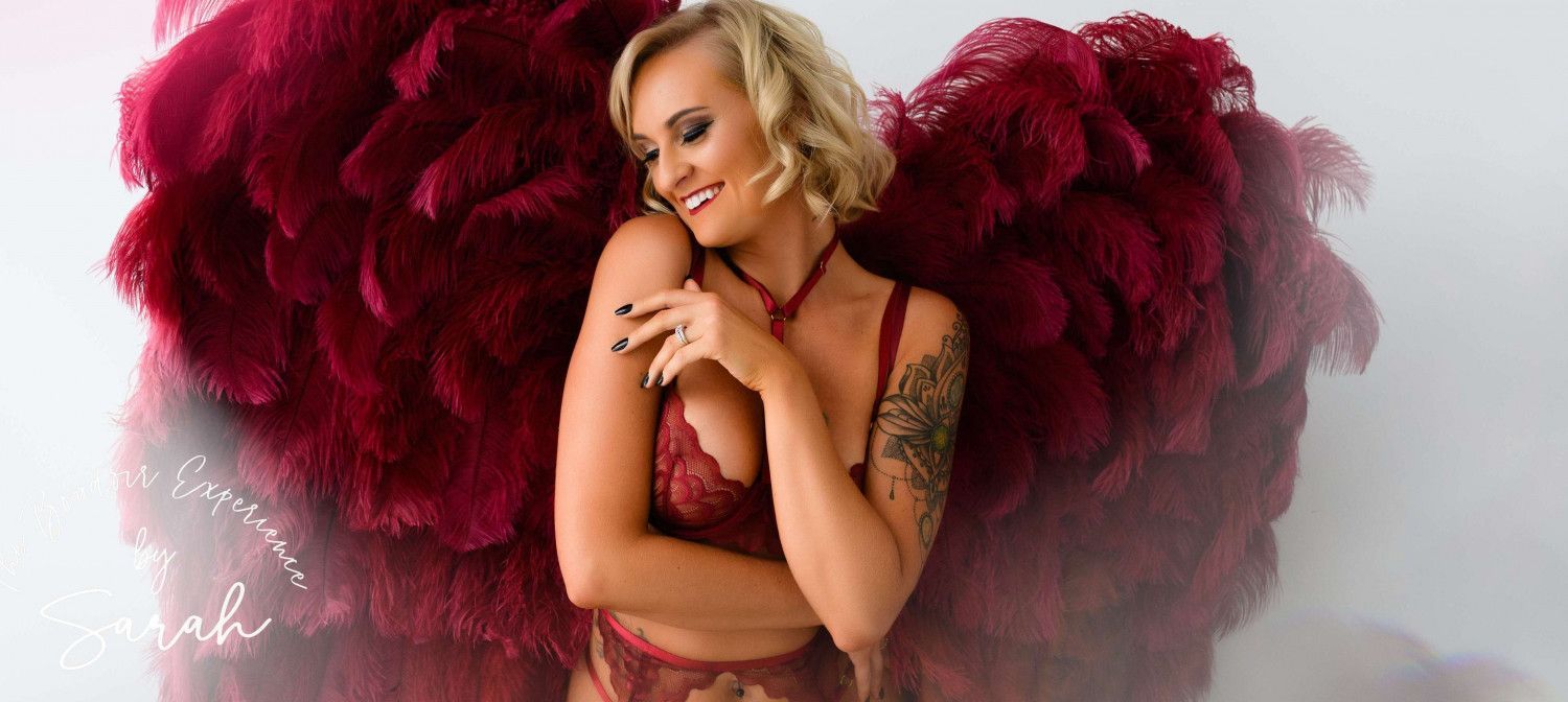 A woman in lingerie is wearing red feather wings.